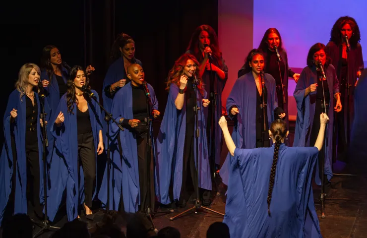 coro femenino de gospel con sus túnicas azules sobre un escenario
