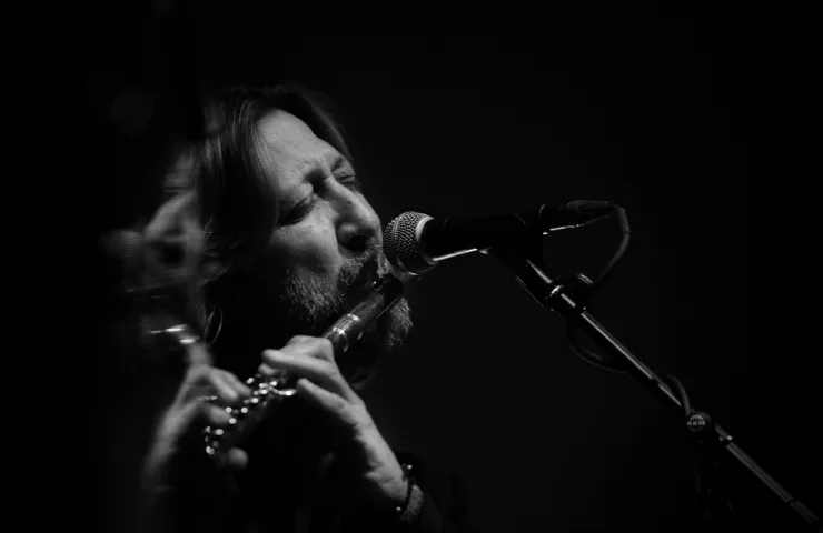 Primer plano de hombre sobre fondo oscuro tocando la flauta