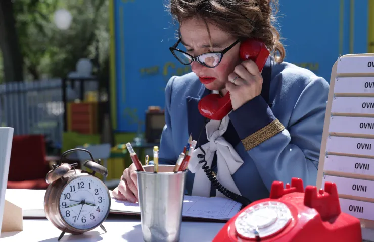 señora hablando por teléfono, en mesa de trabajo, bote de lápices, reloj sobre la mesa