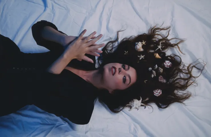 solea morente, tmbada sobre una tela blanca, pelo largo negro y rizado extendido sobre la tela, manos como si fueran a palmear